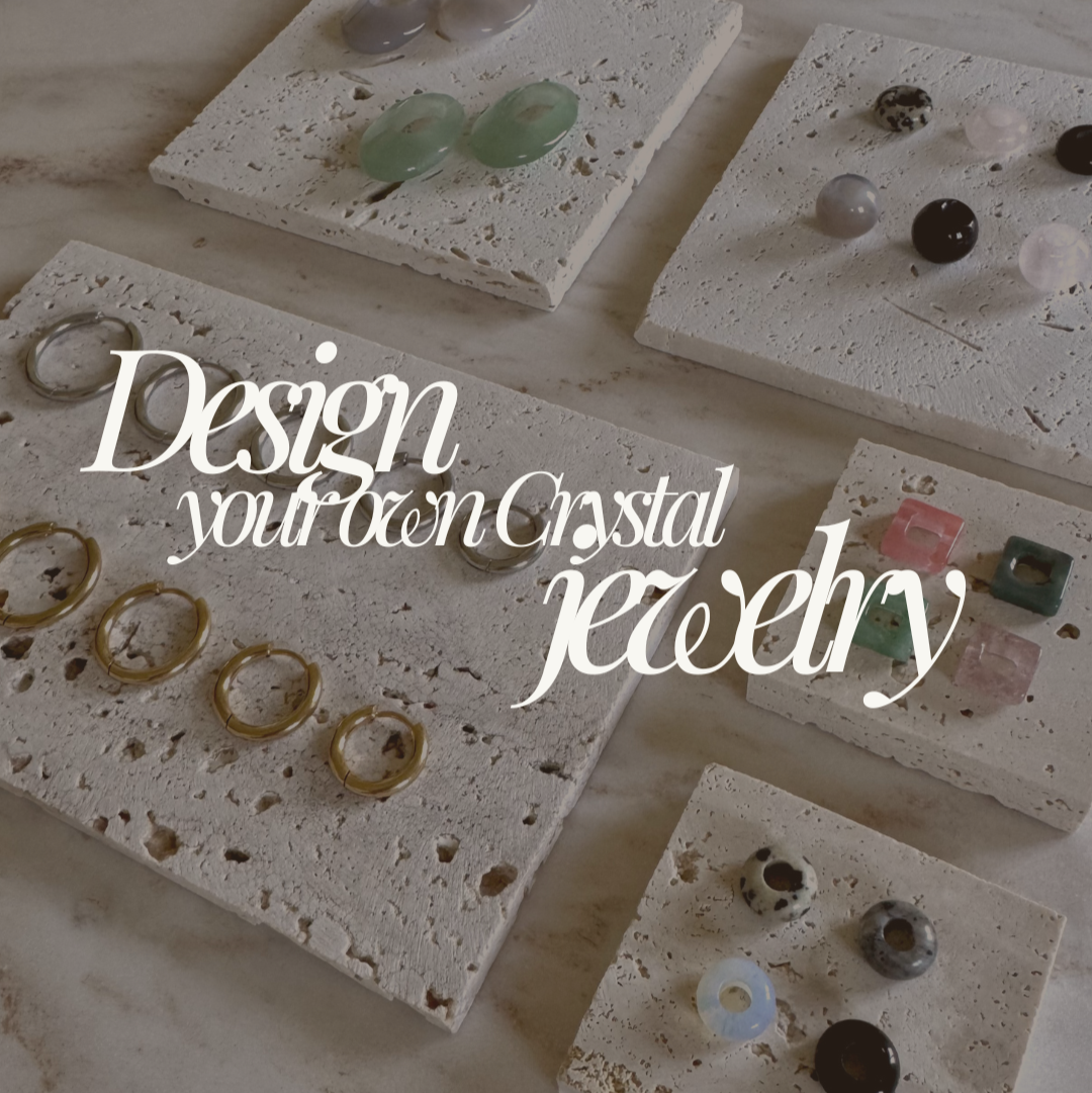 Gold and silver hoop earrings in 5 different sizes and colorful crystal pendants on white stone display