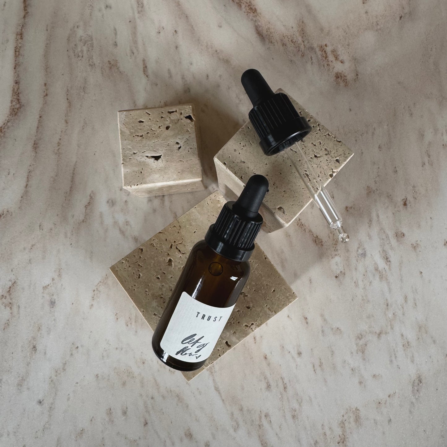Ritual Oil Trust in brown bottle with Dropper on beige stone display