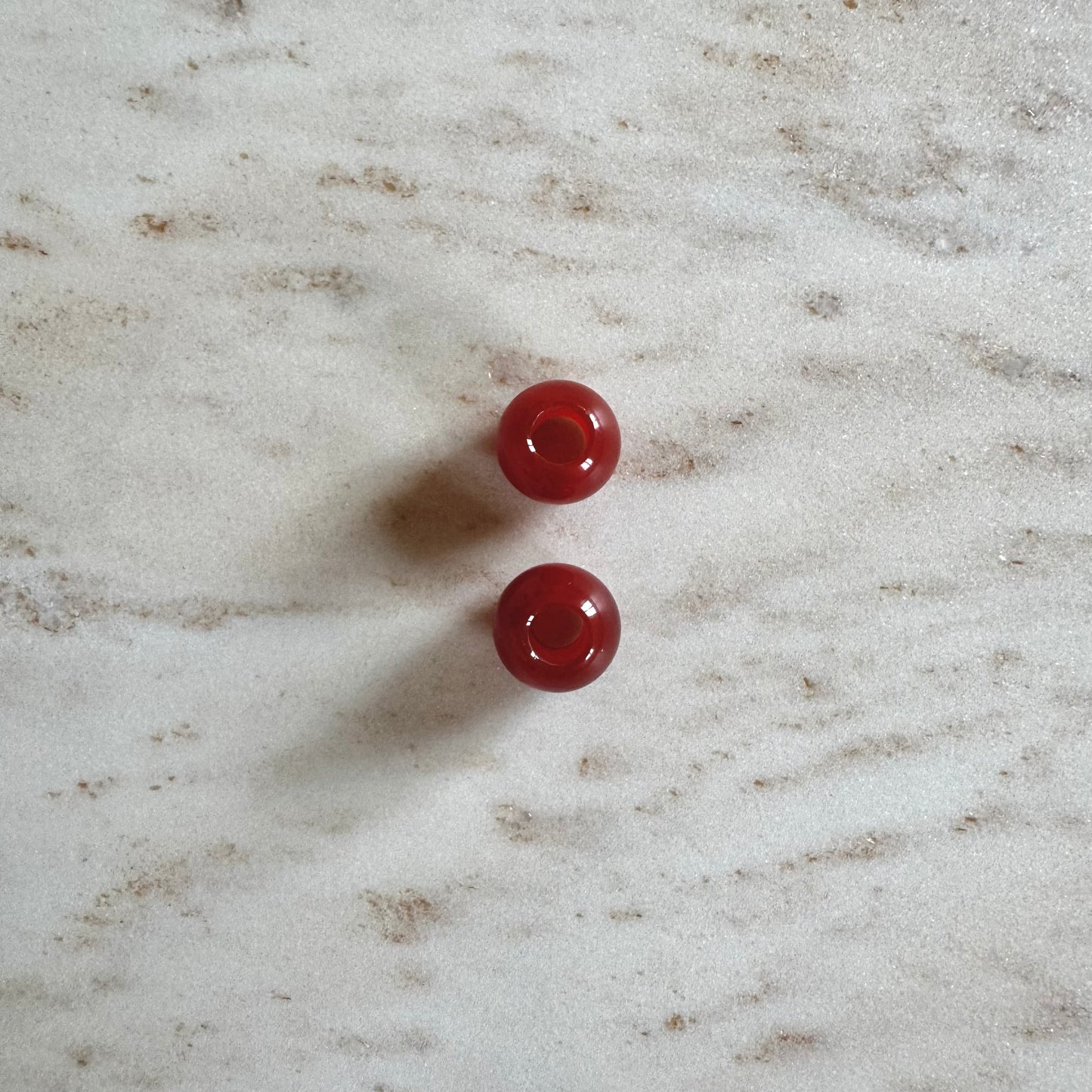 2 rote Achat Anhänger Ballform auf weissem Marmor Stein