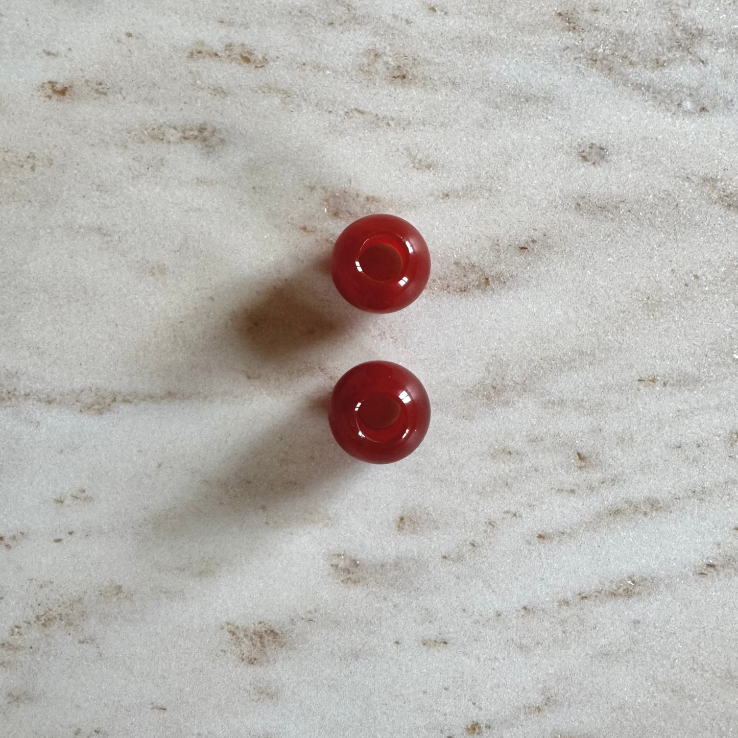 2 rote Achat Anhänger Ballform auf weissem Marmor Stein