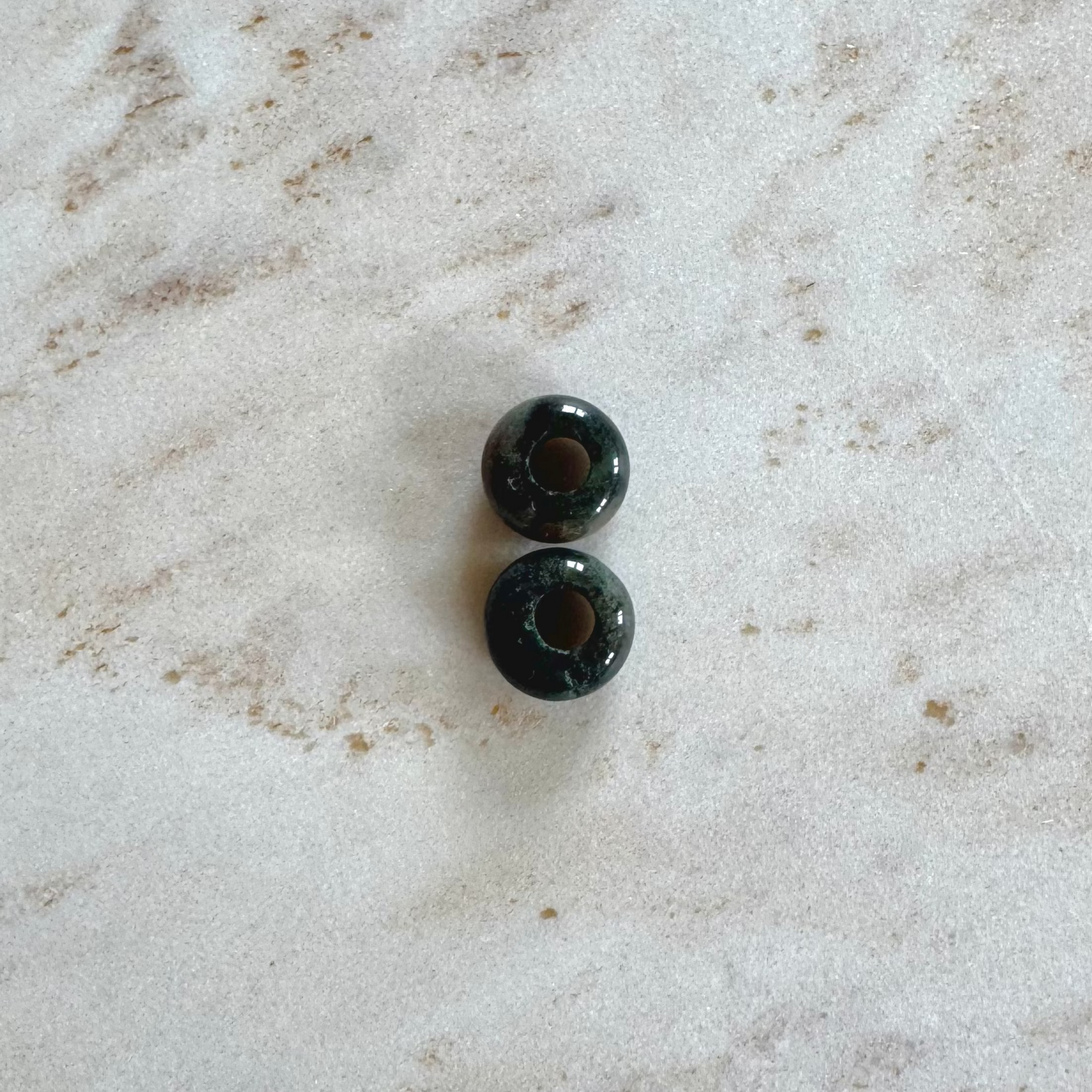  2 green agate donut pendants on beige marble