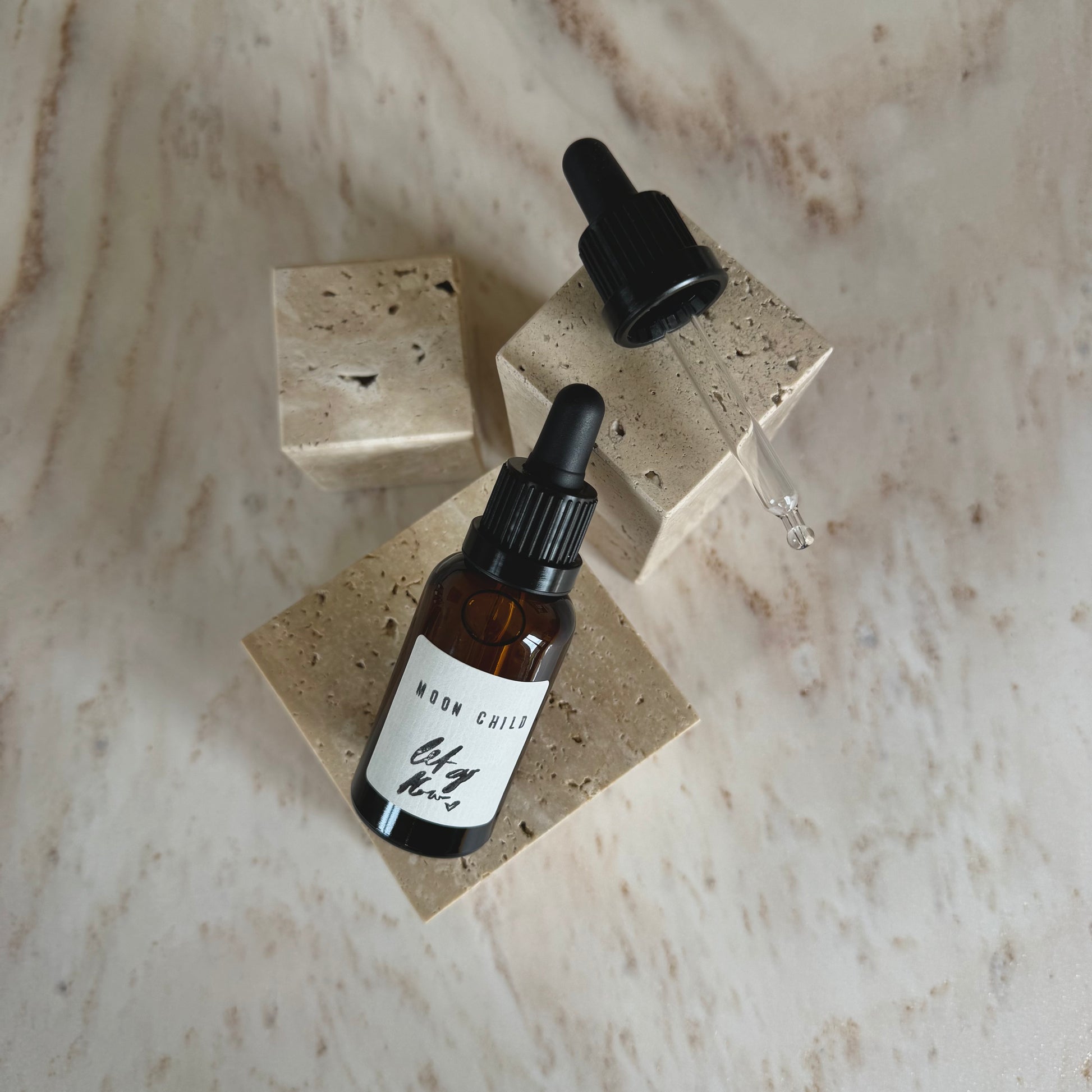 Moon Child Ritual Oil in brown bottle with dropper on beige stone display