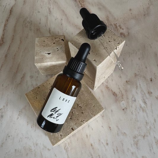 Ritual Oil Love in brown bottle with dropper on beige stone display