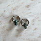 Two silvery hoop earrings on top of each other with 2 green agate donut pendants on beige marble
